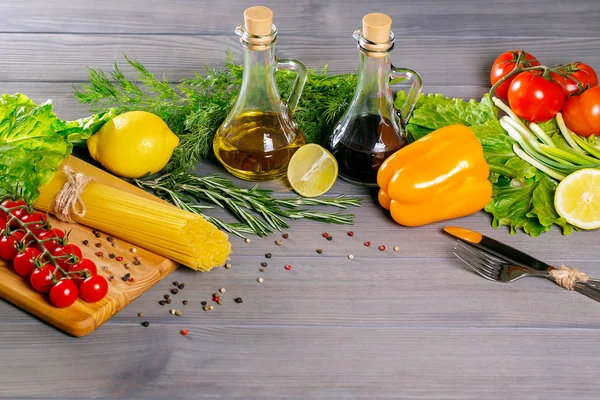 Spaghetti, pomodorini ciliegia, olio d'oliva, erbe aromatiche e spezie su fondo grigio antico. Set per cibi sani. Ingredienti per insalata — Foto Stock