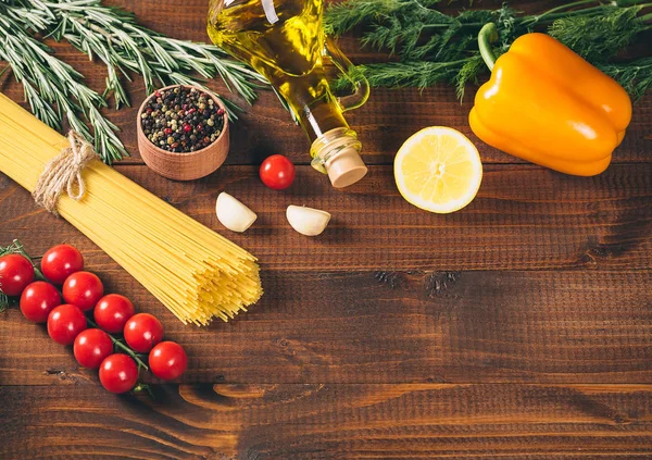 Espaguete, tomate cereja, azeite, ervas e especiarias no fundo de madeira marrom velho . — Fotografia de Stock