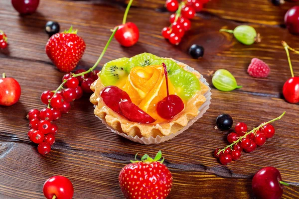 Delicioso bolo de frutas em fundo de madeira marrom com morangos, cerejas, groselhas e framboesas. Sobremesas bonitas, deliciosas e saudáveis — Fotografia de Stock