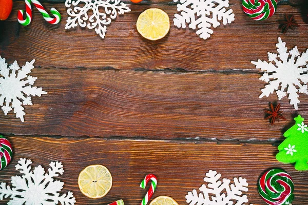Kerstmis achtergrond met sneeuwvlokken, kegels, snoepjes, gedroogd sinaasappelen en citroenen — Stockfoto