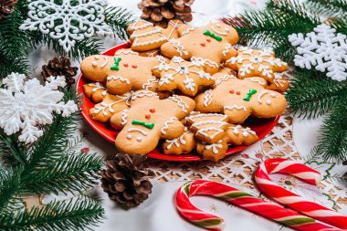Noel gingerbread çerezleri Noel ağacı ve dekor ev yeni yıl masada dalları ile kırmızı plaka üzerinde ev yapımı. Neşeli Noel Kartpostalı