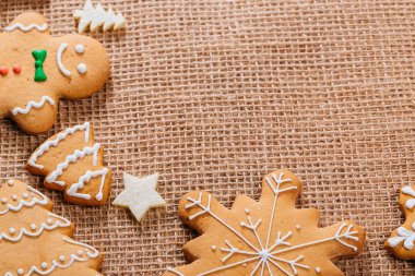 Noel gingerbread çerezleri ev yapımı ve yılbaşı dekor çuval bezi masa örtüsü ile masada. Neşeli Noel Kartpostalı. Çerçeve ile özgür yer