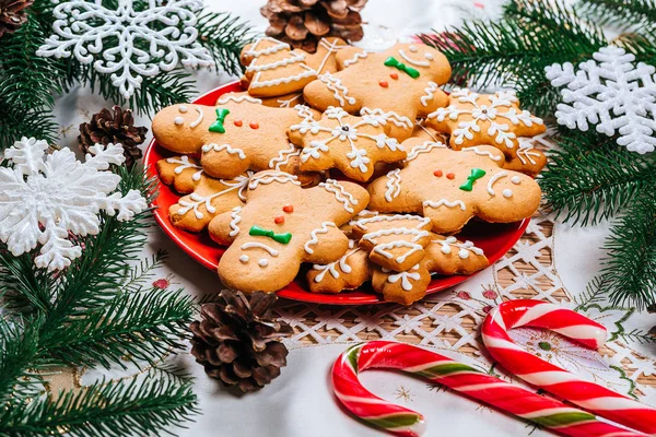 Noel gingerbread çerezleri Noel ağacı ve dekor ev yeni yıl masada dalları ile kırmızı plaka üzerinde ev yapımı. Neşeli Noel Kartpostalı