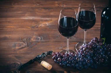 Kırmızı şarap ve üzüm ahşap arka plan üzerinde iki Şarap kadehi.