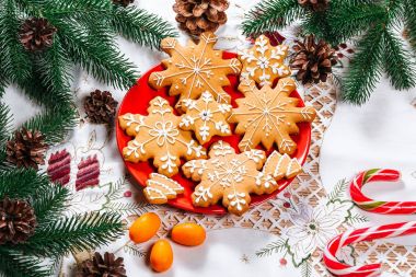 Noel gingerbread çerezleri Noel ağacı ve dekor ev yeni yıl masada dalları ile kırmızı plaka üzerinde ev yapımı. Neşeli Noel Kartpostalı