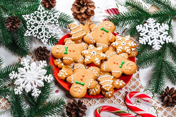 Noel gingerbread çerezleri Noel ağacı ve dekor ev yeni yıl masada dalları ile kırmızı plaka üzerinde ev yapımı. Neşeli Noel Kartpostalı