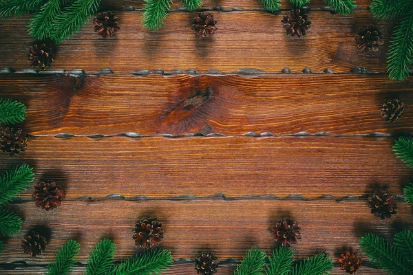 Composición navideña. Marco de Navidad con conos de pino, ramas de abeto sobre fondo marrón madera. Puesta plana, vista superior, espacio libre — Foto de Stock