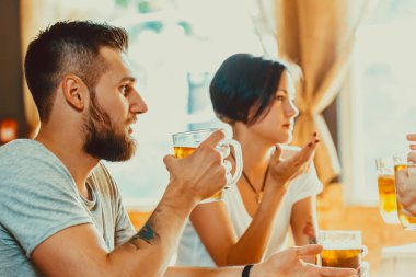 Barda hafif bira gözlük ile toasting arkadaşlar. Güzel arka plan Oktoberfest alanı. Bir grup genç insan barda yorgunluk. ince taneli. Yumuşak odak. Sığ Dof