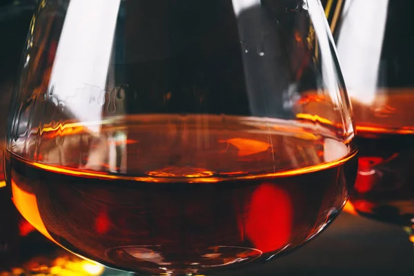 Two glasses of brandy or cognac and bottle on the wooden table.