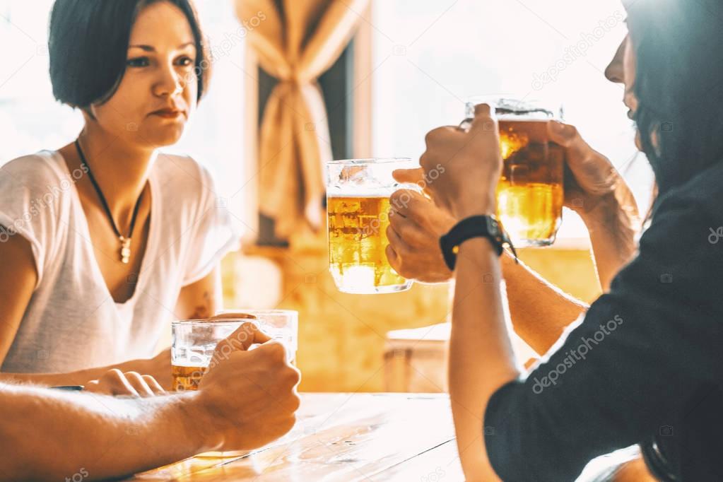 Friends toasting with glasses of light beer at the pub. Beautiful background of the Oktoberfest. A group of young people while relaxing at the bar. fine grain. Soft focus. Shallow DOF