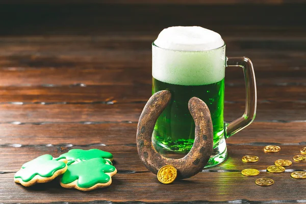 帕特里克节背景与一杯绿色啤酒, 三叶草和马蹄姜饼与金币的木质背景 — 图库照片