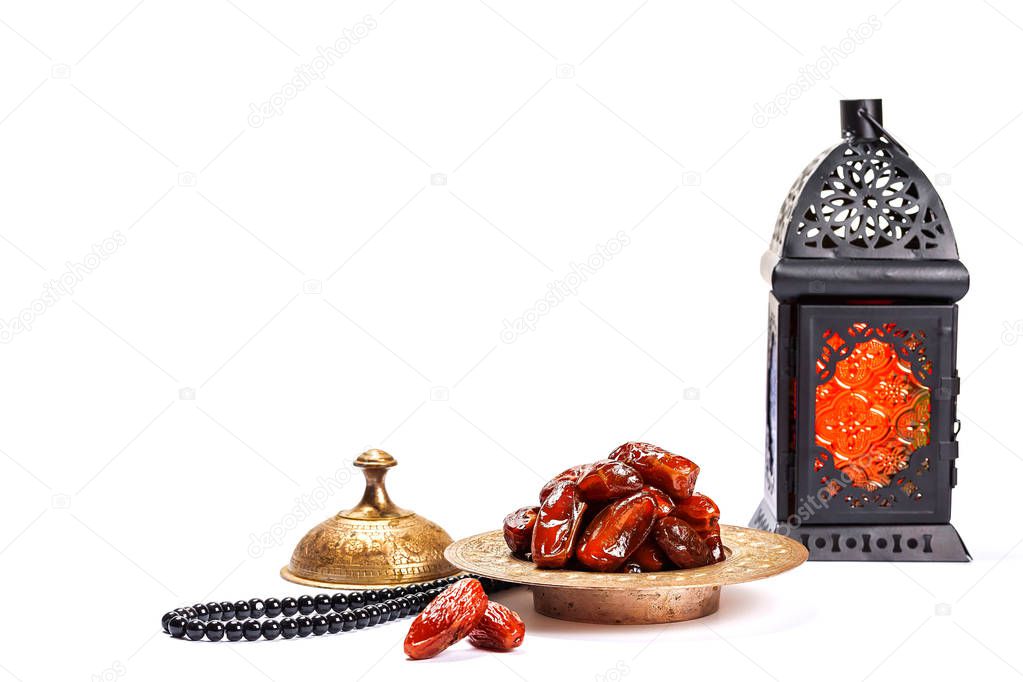 The Muslim feast of the holy month of Ramadan Kareem. Beautiful background with a shining lantern Fanus and dried dates on white. Free space for your text