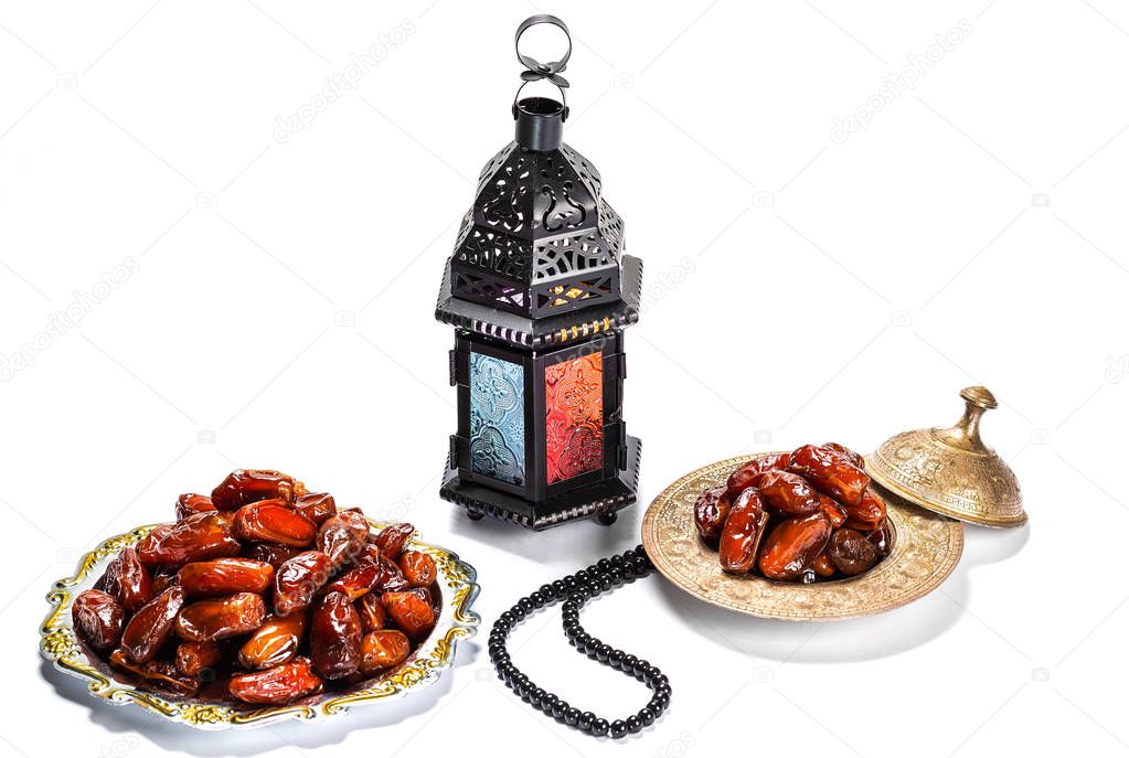 The Muslim feast of the holy month of Ramadan Kareem. Beautiful background with a shining lantern Fanus and dried dates on white. Free space for your text