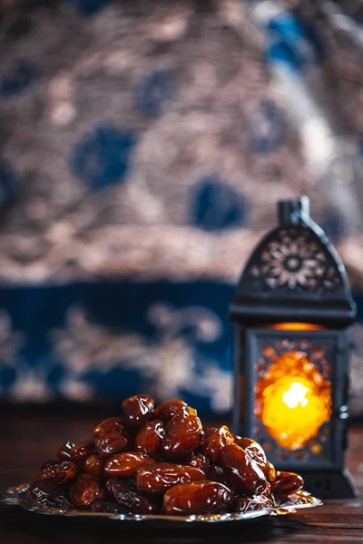 The Muslim feast of the holy month of Ramadan Kareem. Beautiful background with a shining lantern Fanus and dried dates on wooden boards. Free space for your text