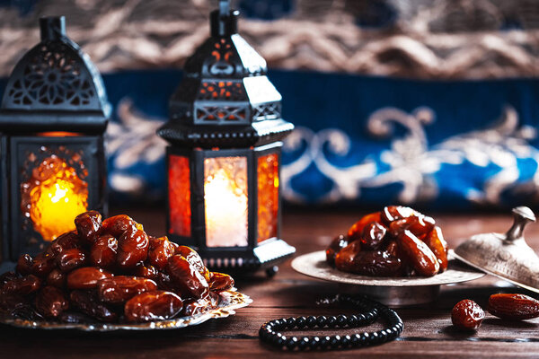 The Muslim feast of the holy month of Ramadan Kareem. Beautiful background with a shining lantern Fanus and dried dates on wooden boards. Free space for your text