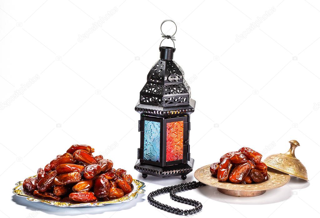 The Muslim feast of the holy month of Ramadan Kareem. Beautiful background with a shining lantern Fanus and dried dates on white. Free space for your text