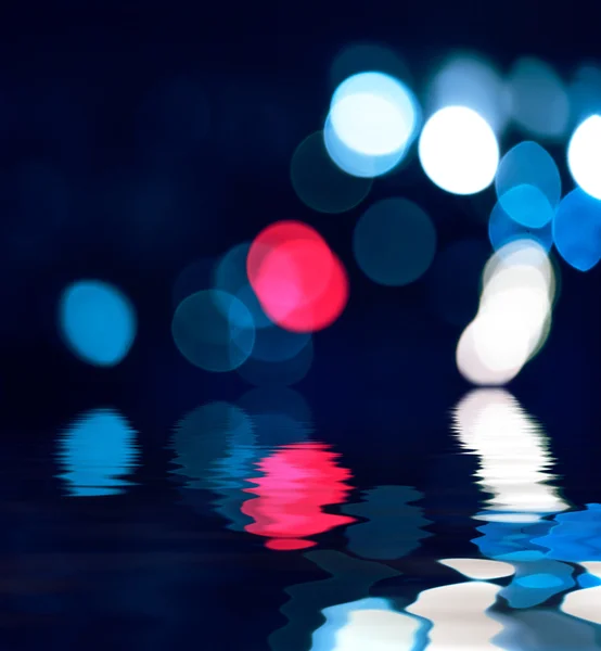Blurred reflection in water of defocused lights at night — Stock Photo, Image