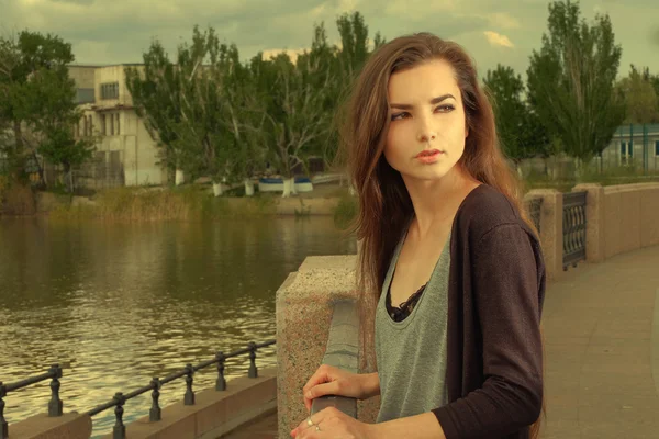 Menina bonita vestindo camisa preta, em pé contra cerca pelo rio Volga em Astrakhan no verão, olhando para trás, efeito filtrado . — Fotografia de Stock