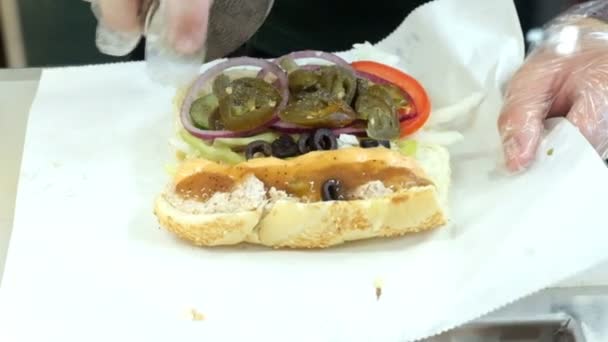 Uno chef prepara un panino con condimenti — Video Stock