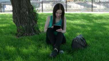 Genç kadın üzerinde tablet Pc geçti çim ayak üzerinde oturan