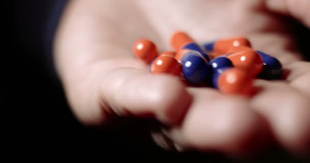 Geneeskunde pillen of capsules in hand, geneesmiddel, remedie voor gezondheid. Antibiotica, pijnstiller op palm close-up. Vrouw oranje-blauw pillen op haar palm mengen — Stockvideo