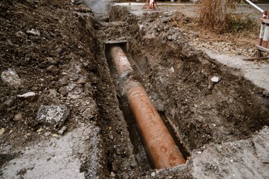 Rusty water pipe in the trench ground view clipart