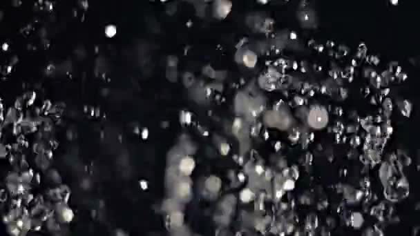 Macro shot de gotas de água voadoras entrando e fora de foco o escuro — Vídeo de Stock