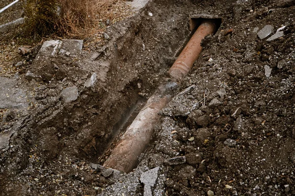 Ancien tuyau rouillé pour l'eau dans une tranchée ouverte pour la réparation vue du dessus — Photo