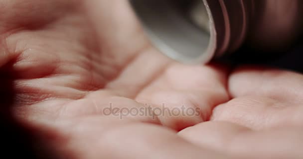 Mujer derrama píldoras blancas de botella de plástico en su palma — Vídeo de stock