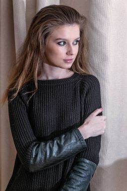 Siyah giymek kapalı poz içinde çekici sarışın seksi. Perde önünde siyah kazak giyen şehvetli kadın portresi. Uzak bir perde karşı ayakta uzun saç seyir ile kadın