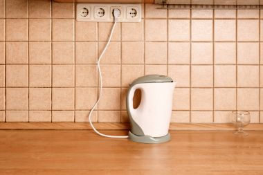Çinili duvar yan görünüm önünde ahşap masa üzerinde elektrikli su ısıtıcısı
