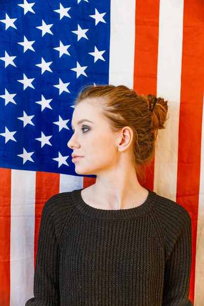 Joven andrógina mirando hacia otro lado frente a las estrellas estadounidenses y bandera de rayas —  Fotos de Stock