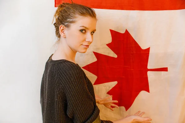 Junges Immigrantenmädchen in schwarzem Pullover blickt zurück und posiert vor der kanadischen Flagge Vintage-Farbbild — Stockfoto