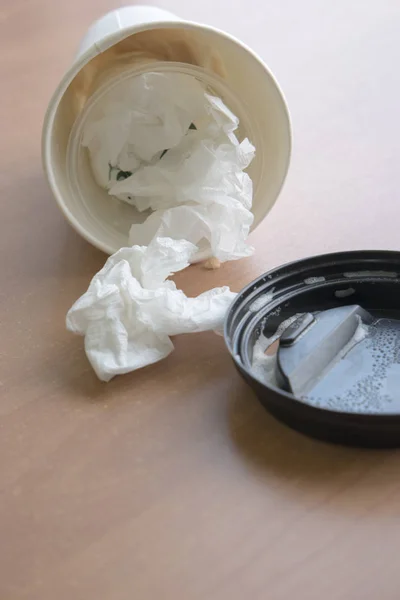 Takeaway cup full of used wipes and its lid near on wooden table — Stock Photo, Image