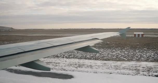 Vista al ala del avión desde la ventana en invierno, nieve en la tierra. Taxiing avión de pasajeros — Vídeos de Stock