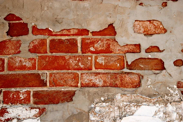 Заброшенная кирпичная стена частично покрыта серой штукатуркой из цемента — стоковое фото