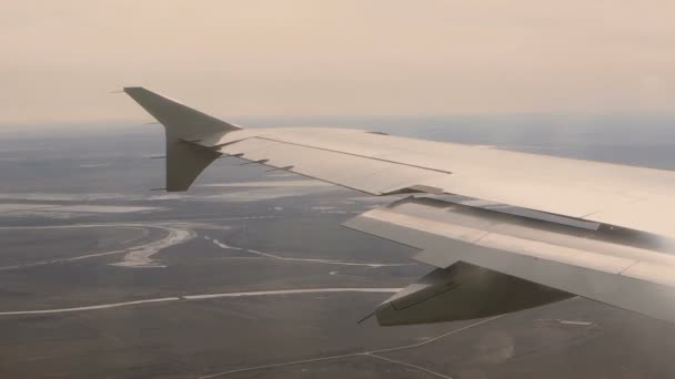 Вид из окна самолета в крыло самолета, земля, река под ним — стоковое видео