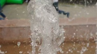 Çeşme su sıçramalarına yavaş hareket Defocused çocuk arka planda çalıştırın