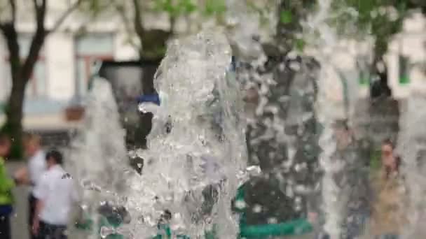 Menschen gehen im Park defokussierte Aufnahmen mit Zeitlupenfontäne im Vordergrund — Stockvideo