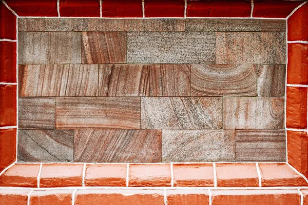 Granite tiles on wall inside frame of bricks