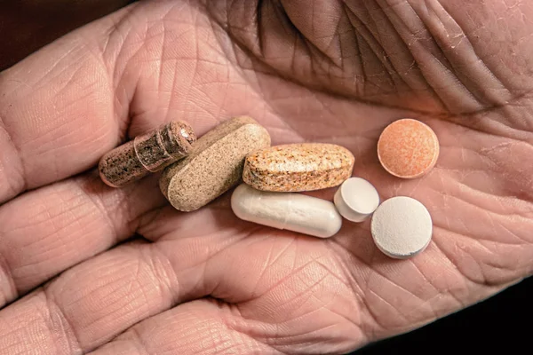 Набор таблеток и таблеток на ладони пожилой женщины сверху — стоковое фото