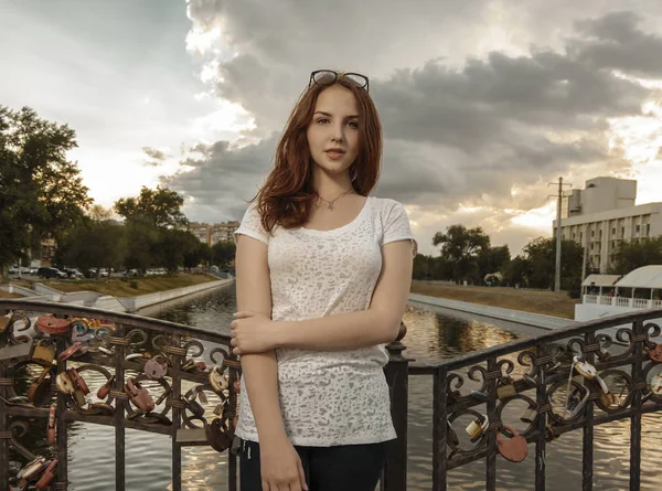 Femme mignonne sur le pont avec des serrures d'amour sur la clôture regardant la caméra — Photo