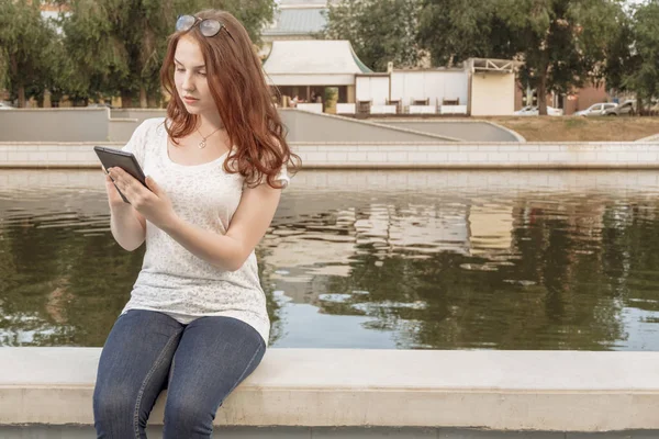 Young gingerish woman work with tablet pad in park — Stock Photo, Image