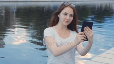Açık bir dokunmatik tablet kullanan bir gülümseyen genç kız portresi