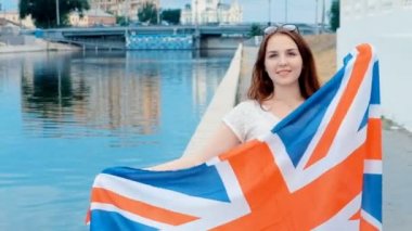 Rahat tarzı elleri büyük Britanya bayrağı ile gülümseyen güzel genç kız. Kızıl saçlı, su arka plan üzerinde. Vintage renk değerlendirme.