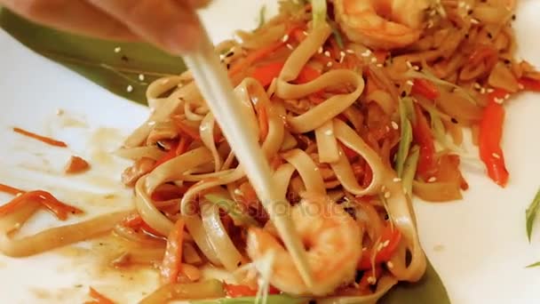 Mujer comiendo mariscos chinos con camarones y fideos usando palillos — Vídeo de stock