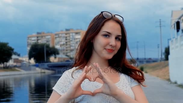 Рыжая девушка с волосами заставила руку подписать сердце своими пальцами — стоковое видео