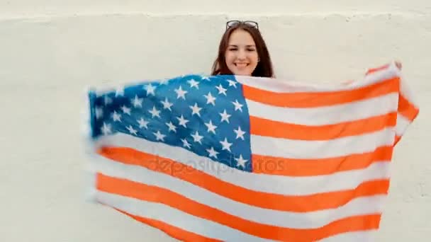 Mujer orgullosa con la bandera americana y amplia sonrisa. Retrato de una encantadora joven pelirroja con bandera de los Estados Unidos ondeando — Vídeos de Stock