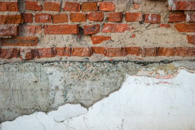 Yarısı çimento ile kaplı ve beyaz renkte boyalı eski kırmızı tuğla duvar