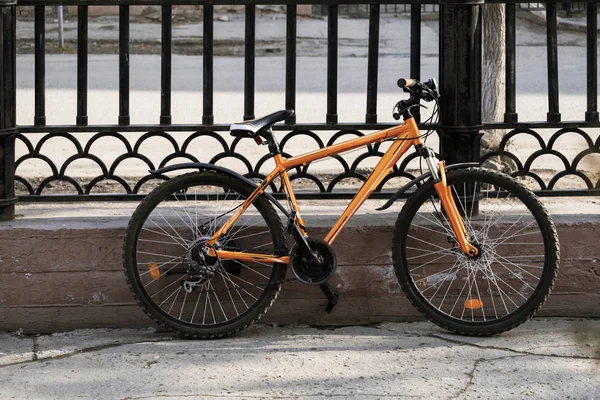 Modern style mountain bicycle locked by the fence in city street in the city — Stock Photo, Image